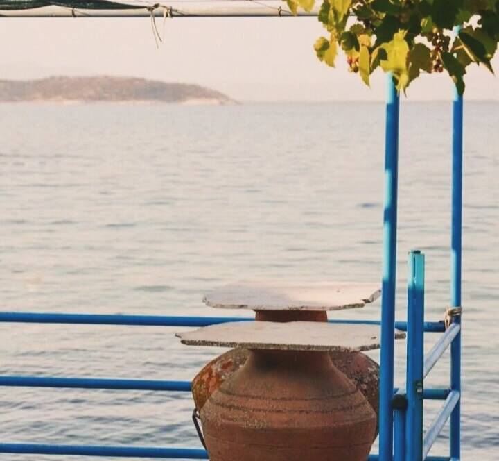 Clay jars on a sunlit terrace overlooking the Aegean Sea at The Old Pottery Retreat in Thassos.